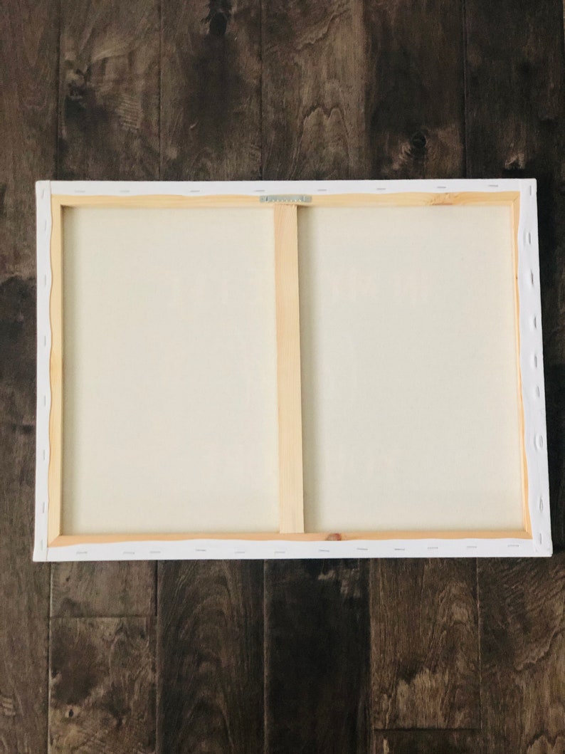 May include: The back of a stretched canvas painting with a wooden frame. The canvas is white and the frame is natural wood.