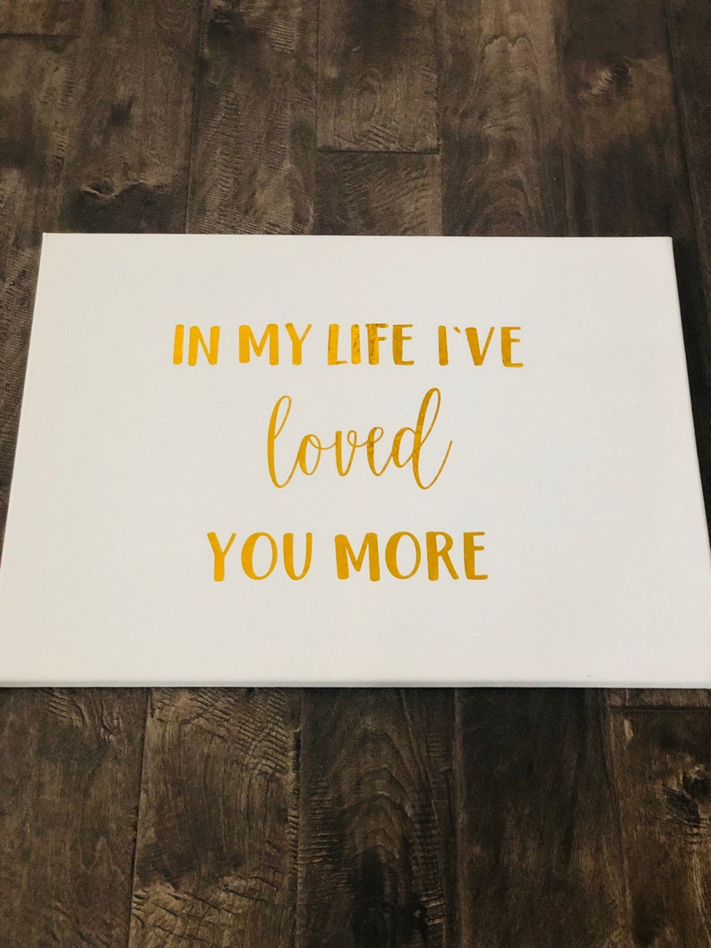 May include: White canvas with gold lettering that reads "In my life I've loved you more".