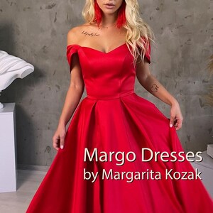 May include: A woman wearing a red off-the-shoulder gown with a sweetheart neckline. The gown has a full skirt and is made of a satin fabric. The text "Margo Dresses by Margarita Kozak" is displayed at the bottom of the image.