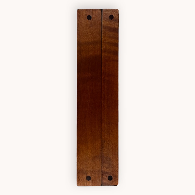 May include: Two wooden panels joined together with black metal hinges. The panels are a rich brown color and have a smooth, polished finish. Each panel has two black metal screws at the top and bottom.