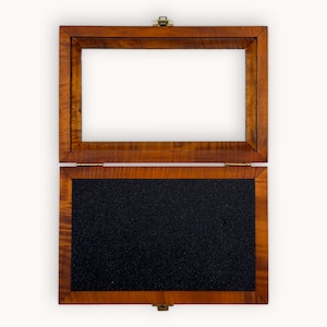 May include: A wooden box with a hinged lid. The box is open, revealing a black foam interior.