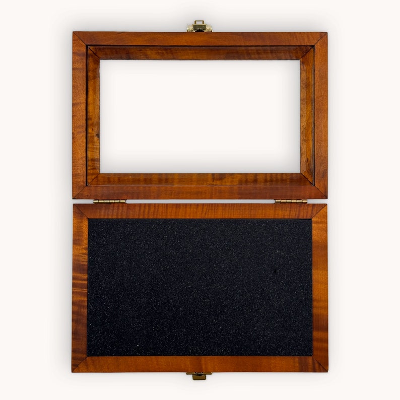 May include: A wooden box with a hinged lid. The box is open, revealing a black foam interior.