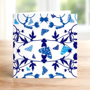 Puede incluir: Tarjeta de felicitación blanca con un diseño de mariposas y flores azules. Las mariposas tienen un patrón moteado y están en varios tonos de azul. Los elementos florales son de color azul oscuro.