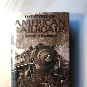 May include: The Story of American Railroads by Stewart H. Holbrook book cover featuring a black and white photograph of a steam locomotive with the text "Over 100 Illustrations" at the bottom.