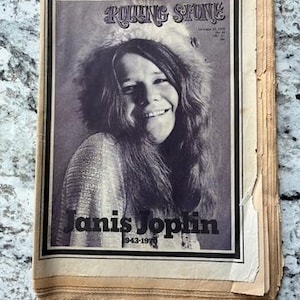 May include: A vintage Rolling Stone magazine cover from October 29, 1970, featuring a black and white portrait of Janis Joplin. The text reads Rolling Stone, October 29, 1970, No. 69, 50c, and Janis Joplin 1943-1970. The paper edges are aged and yellowed.