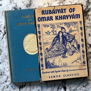 May include: Two vintage books titled "Rubaiyat of Omar Khayyam" are displayed. One is blue with gold lettering and a gold medallion. The other is tan with blue illustrations and text, including "Rendered into English Verse by Edward Fitzgerald."
