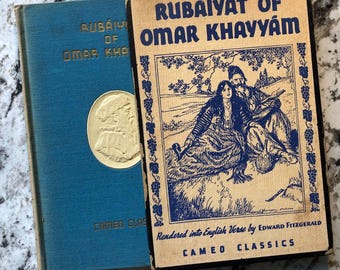 Könnte beinhalten: Zwei alte Bücher mit dem Titel "Rubaiyat of Omar Khayyam" werden gezeigt. Eines ist blau mit goldener Schrift und einem goldenen Medaillon. Das andere ist beige mit blauen Illustrationen und Text, einschließlich "Rendered into English Verse by Edward Fitzgerald".