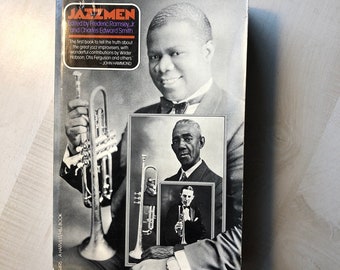 May include: A black and white photo of a book titled "Jazzmen" edited by Frederic Ramsey, Jr. and Charles Edward Smith. The book cover features a black and white photo of a man playing a trumpet. The text on the cover reads "The first book to tell the truth about the great jazz improvisers, with wonderful contributions by Wilder Hobson, Otis Ferguson and others - JOHN HAMMOND."