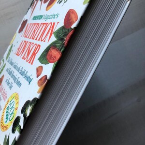 May include: A white hardcover book titled "Prevention Magazine's Nutrition Advisor: The Ultimate Guide to the Health-Boosting and Disease-Preventing Foods in Your Diet" with a colorful image of vegetables and fruits on the cover. The book has over 1,000 recipes.