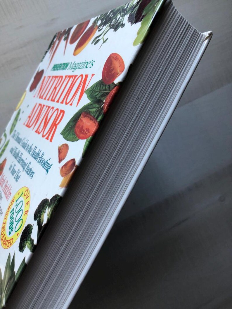 May include: A white hardcover book titled "Prevention Magazine's Nutrition Advisor: The Ultimate Guide to the Health-Boosting and Disease-Preventing Foods in Your Diet" with a colorful image of vegetables and fruits on the cover. The book has over 1,000 recipes.