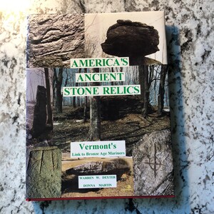 May include: A book titled "America's Ancient Stone Relics" with a collage of stone images and forest scenes. The cover also includes the text "Vermont's Link to Bronze Age Mariners" and the authors' names, Warren W. Dexter and Donna Martin.