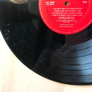 May include: A red vinyl record with the title "The Party's Over" by Diahann Carroll and The Andre Previn Trio. The record is labeled "IJAL 3069" and "Side 1".