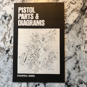 May include: A black book titled "PISTOL PARTS & DIAGRAMS" with a detailed diagram of a pistol's components. The book is from Stackpole Books. The diagram is in black and white.