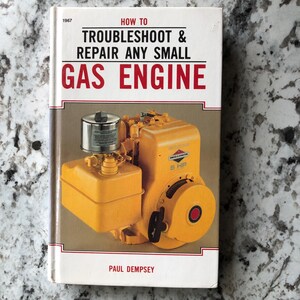 May include: A vintage book titled "How to Troubleshoot & Repair Any Small Gas Engine" with a yellow gas engine illustration. The book cover features the text "1967" and the author's name, Paul Dempsey.