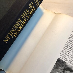 K&ouml;nnte beinhalten: Ein schwarzes Hardcover-Buch mit goldenen Lettern auf dem R&uuml;cken. Der Titel lautet "Der Kardinal des Kremls" von Tom Clancy.