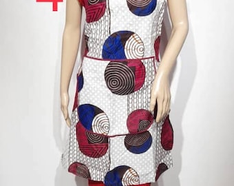 May include: A white apron with a colorful circular pattern of blue, red, and brown circles. The apron has a red neckline and trim. The number 4 is visible in the upper left corner. The apron is displayed on a mannequin.