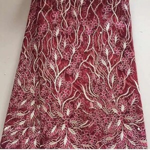 May include: Burgundy lace fabric with a floral pattern in white. The fabric is delicate and has a soft, flowing texture.