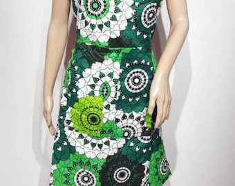May include: A green, white, and red patterned dress with a red bodice and a green and white skirt. The dress has a round neckline and a sleeveless design. The dress is on a mannequin.