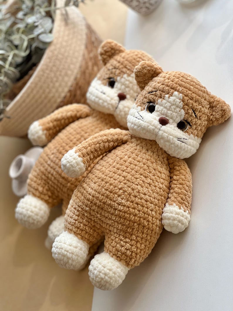 Pu&ograve; includere: Due bambole a forma di gatto all'uncinetto fatte a mano. Le bambole sono color beige con dettagli bianchi sul viso, sulle zampe e sui piedi. Gli occhi sono neri e il naso &egrave; marrone. Le bambole sono morbide e soffici.