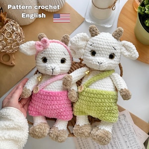 May include: Two handmade crochet goat dolls. One goat wears a pink skirt and headband, the other a green skirt. Both have white bodies, brown accents, and button details. The text "Pattern crochet English" is at the top.