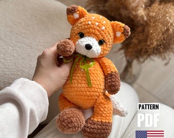 May include: Crocheted orange fox plush toy with white accents and a green ribbon. The toy is being held by a hand. The text "PATTERN PDF" is visible in the image.