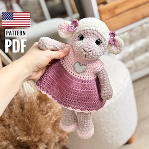 May include: Crochet amigurumi pattern for a pink and white sheep wearing a pink dress with a silver heart. The pattern is available as a PDF download.