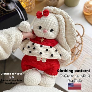 May include: A handmade crochet bunny doll wearing a red and white outfit with black polka dots. The bunny has long, floppy ears, a red bow, and a flower accent. The image includes text that says "Clothes for toys" and "Clothing pattern!" with the word "English" and the American flag.
