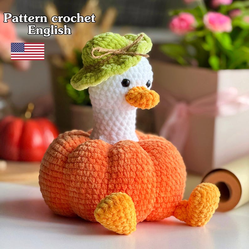 May include: A handmade crochet goose doll with a pumpkin body, wearing a green hat. The goose has a white head, orange beak, and black eyes. The text "Pattern crochet English" is visible in the image.