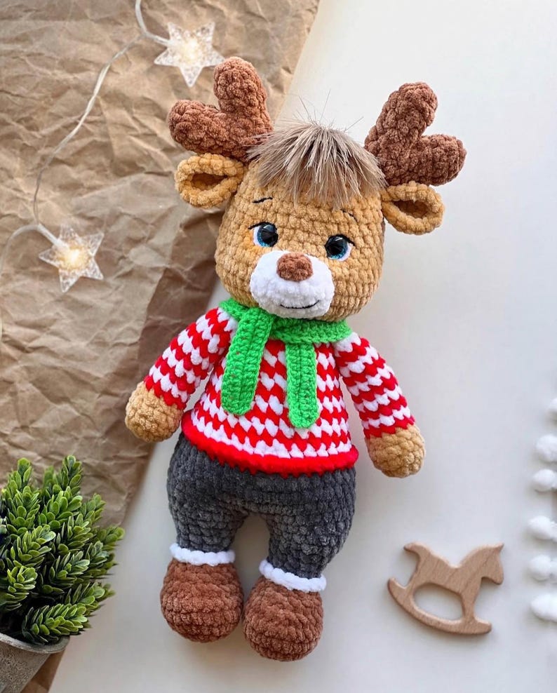 May include: A handmade crochet reindeer doll with brown antlers, a green scarf, and a red and white striped sweater. The reindeer has gray pants, brown shoes, and blue eyes. A charming holiday decoration.