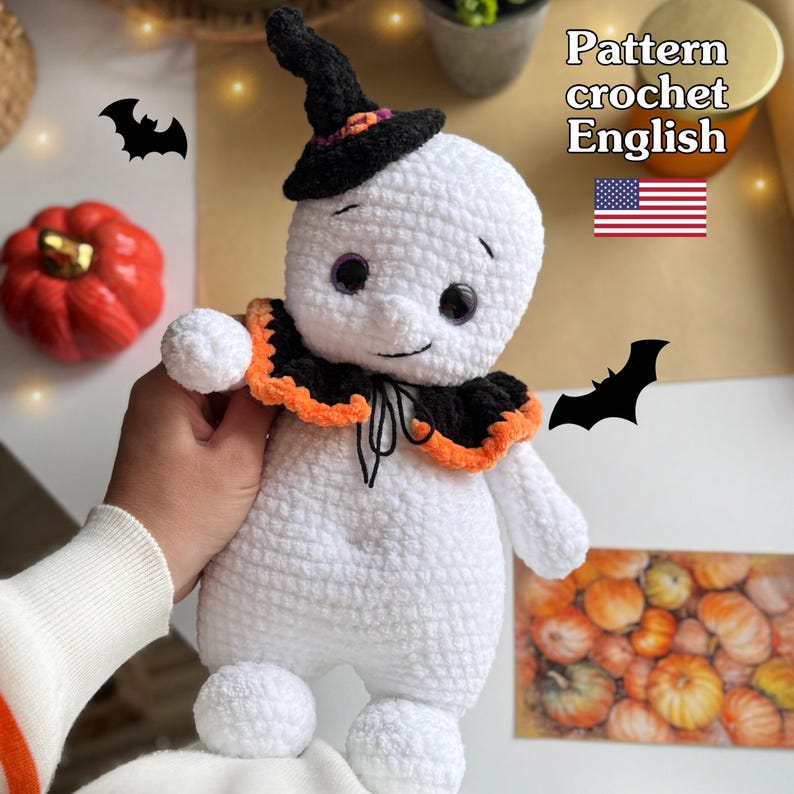 May include: A white crochet ghost doll with a black witch's hat and orange and purple details. The ghost has a black and orange collar and purple eyes. The image includes the text "Pattern crochet English" and a small American flag.