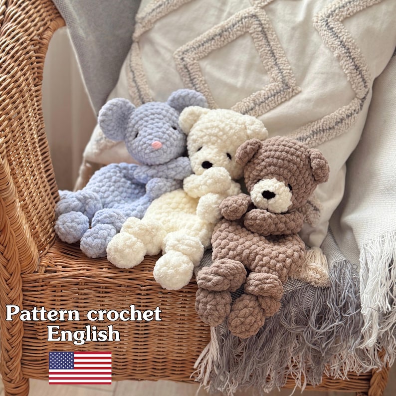 Pode incluir: Tr&ecirc;s ursos de pel&uacute;cia de croch&ecirc; feitos &agrave; m&atilde;o em azul claro, creme e marrom. Os ursos est&atilde;o sentados em uma cadeira de vime com uma almofada decorativa ao fundo. O texto "Pattern crochet English" &eacute; vis&iacute;vel na imagem.