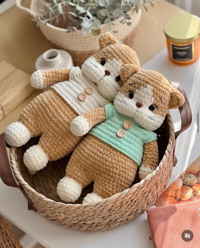 Pu&ograve; includere: Tre bambole a forma di gatto all'uncinetto fatte a mano in un cestino di vimini. Le bambole hanno corpi color beige, dettagli bianchi e indossano maglioni color crema e verde menta. Le bambole hanno chiusure con bottoni e sono in un cestino intrecciato.