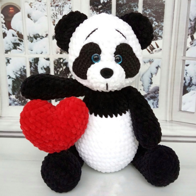 Peut inclure: Une peluche panda noir et blanc tenant un c&oelig;ur rouge. Le panda a des yeux bleus et est fait d'une mati&egrave;re douce et textur&eacute;e. Un cadeau charmant ou un objet d&eacute;coratif pour une chambre d'enfant.