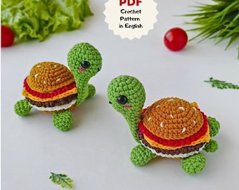 May include: Two crocheted turtle amigurumi toys with a hamburger design. The turtles are green with brown, yellow, red, and white details. The turtles are on a white background.