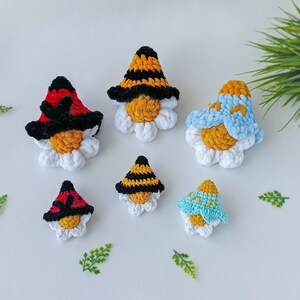 May include: Six crocheted bee and ladybug ornaments with white daisy-like bases. The bees have black and yellow stripes and the ladybugs are red with black spots.