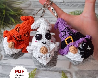 May include: Three crocheted Halloween gnome keychains. One is a pumpkin gnome, one is a ghost gnome with the word "BOO" on its hat, and one is a witch gnome with a purple hat and a black spider.