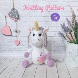 May include: Knitting pattern for a white unicorn amigurumi toy with a pink heart and rainbow yarn. The pattern is available in English and is a PDF download.