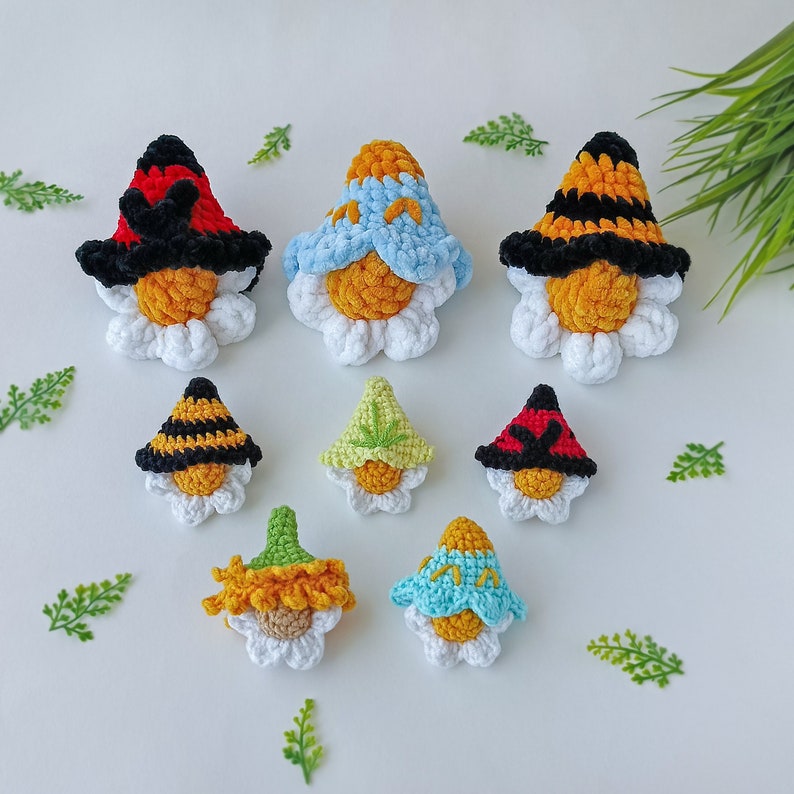 May include: A set of ten crocheted flower-shaped ornaments with different colored hats. The ornaments are made of white yarn and have a yellow center. The hats are red, blue, yellow, green, and black.