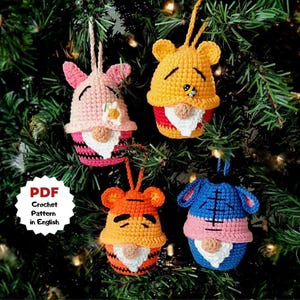 Könnte beinhalten: Vier handgefertigte gehäkelte Zwerg-Ornamente in Rosa, Gelb, Orange und Blau, jedes mit einem anderen Charakterdesign. Die Ornamente hängen an einem Weihnachtsbaum. Der Text "PDF Crochet Pattern in English" befindet sich in der unteren linken Ecke.