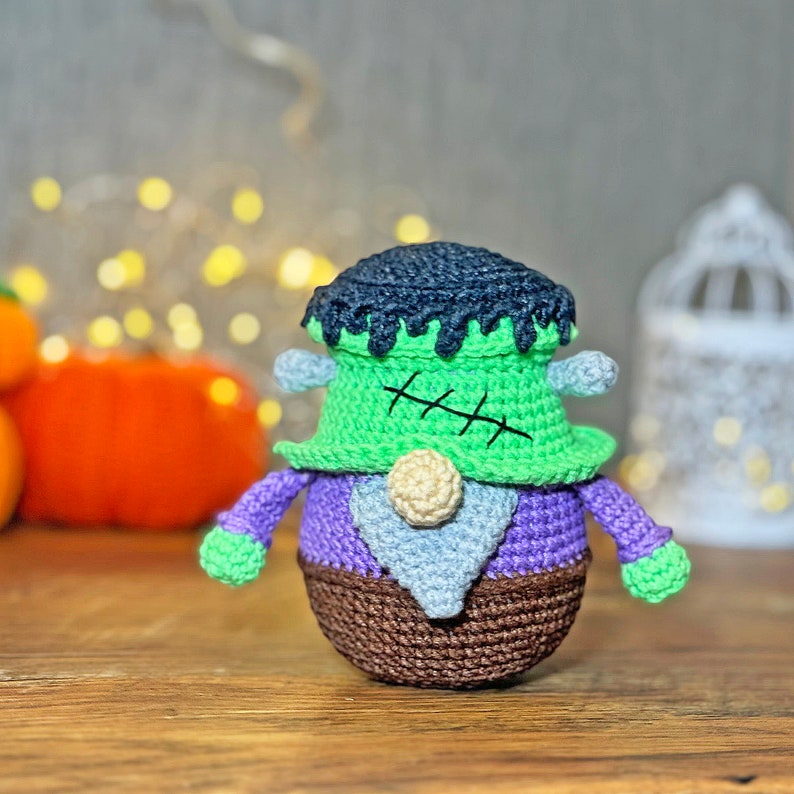 May include: A green and purple crocheted Frankenstein gnome with a black hat and a brown belt.