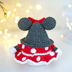 May include: A crocheted Minnie Mouse doll with a red and white polka dot dress and black ears.