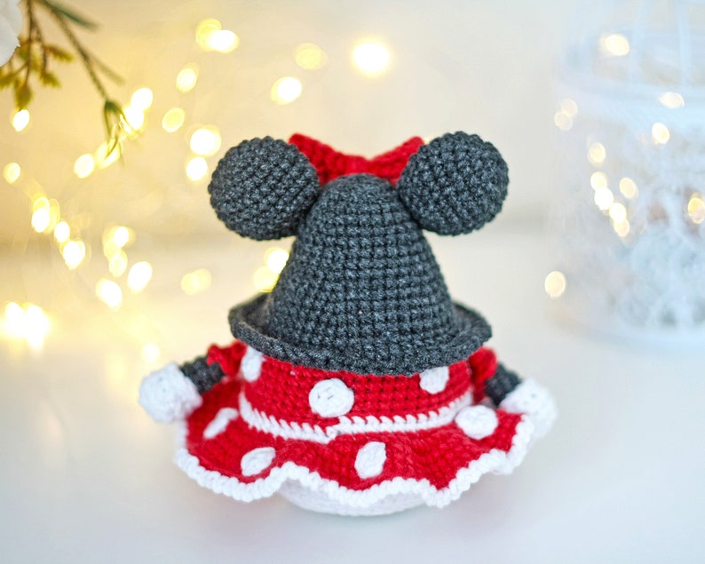 May include: A crocheted Minnie Mouse doll with a red and white polka dot dress and black ears.