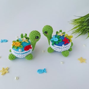 May include: Two crocheted sea turtle toys with colorful details, including flowers, fish, and starfish. The turtles are green with white and blue shells.
