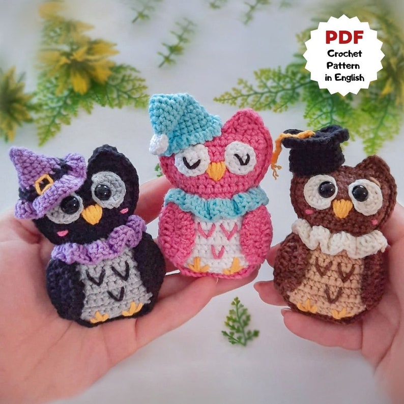 K&ouml;nnte beinhalten: Drei geh&auml;kelte Eulen-Amigurumi-Spielzeuge. Eine Eule tr&auml;gt einen Hexenhut, eine andere tr&auml;gt eine Abschluss-Kappe und die dritte tr&auml;gt eine blaue Schlafkappe.  PDF-H&auml;kelanleitung in Englisch.