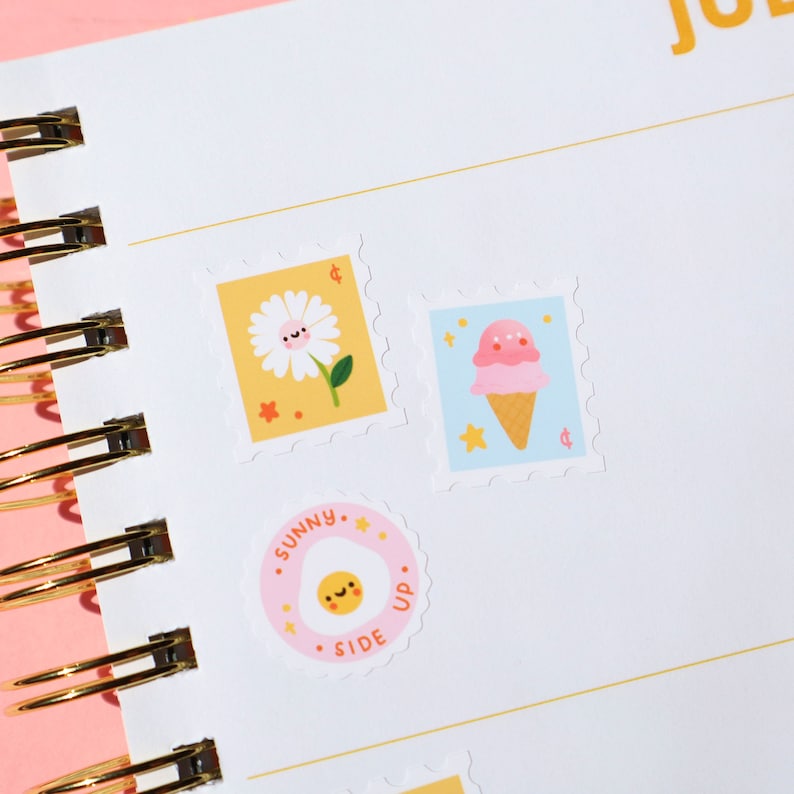 Pu&ograve; includere: Tre adesivi colorati con illustrazioni carine. Un adesivo giallo con una margherita, un adesivo blu con un cono gelato e un adesivo rosa con un uovo fritto.