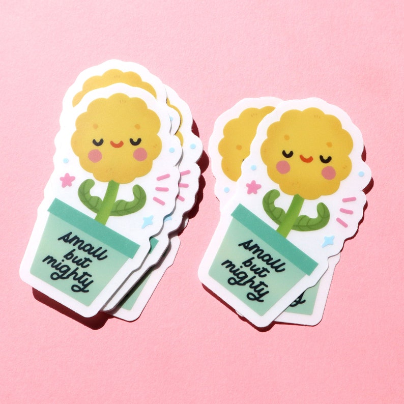 May include: A stack of five yellow flower stickers with green stems and a light green pot. The stickers have a smiling face and the text "small but mighty" on the pot.