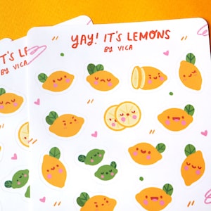 Puede incluir: Una hoja de papel adhesivo blanco con pegatinas de lim&oacute;n de dibujos animados de colores. Las pegatinas muestran limones con diferentes expresiones faciales y algunas pegatinas de lima. El texto "yay! it's lemons by vica" est&aacute; impreso en la parte superior de la hoja.