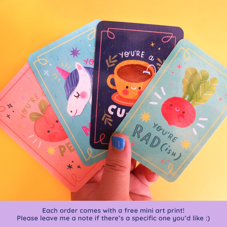 May include: Four colorful cards with illustrations and text. The cards feature a unicorn, a cup of tea, a radish, and an apple. The text on the cards reads "You're a cutie", "You're rad (ish)", "You're a peach", and "You're magic".