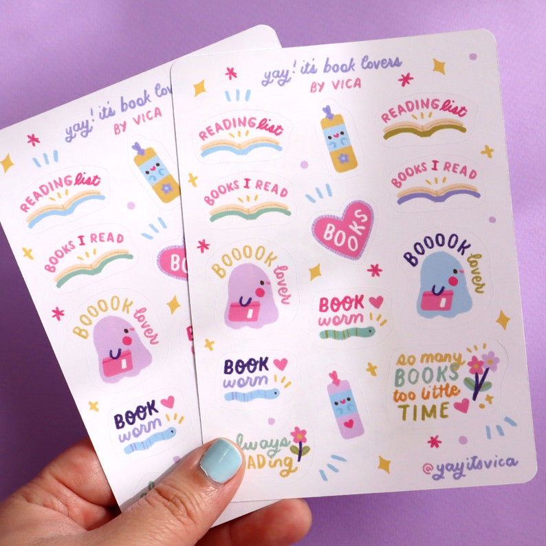May include: Three sheets of stickers with a book lover theme. The stickers feature illustrations of books, ghosts, worms, and hearts. The text on the stickers includes "yay! it's book lovers", "reading list", "books I read", "booook lover", "book worm", "so many books too little time", and "@yayitsvica".