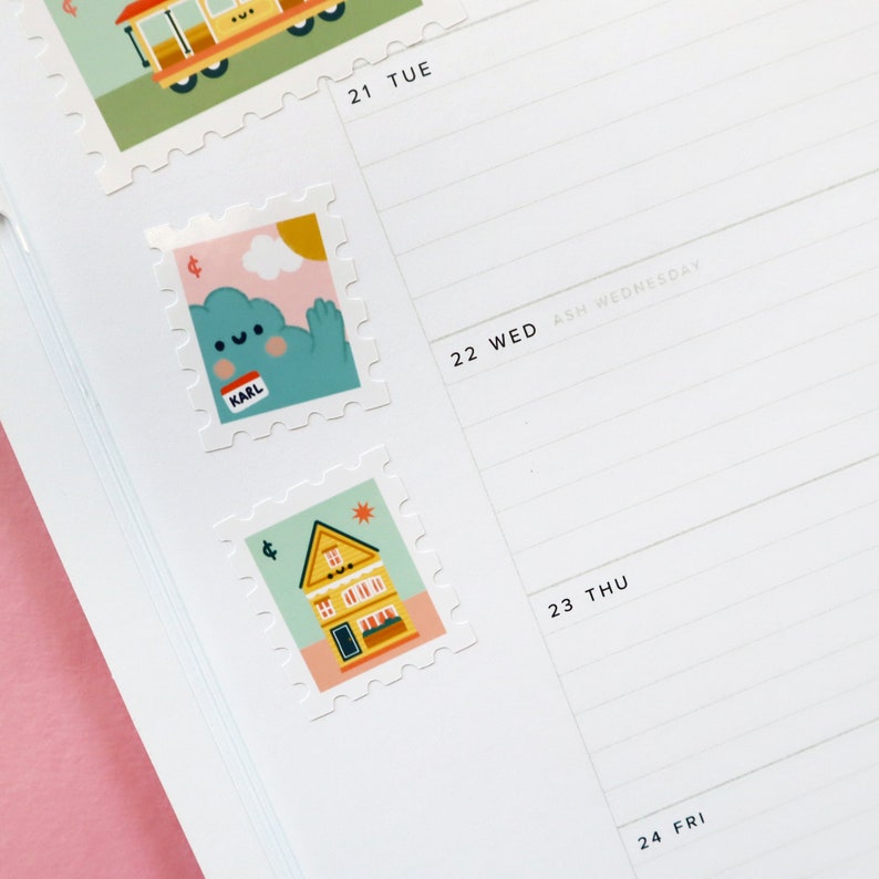 May include: Two colorful stickers with a whimsical design. The first sticker features a blue cloud with a smiling face and the word "KARL" on a name tag. The second sticker features a yellow house with a red roof and a star on top.
